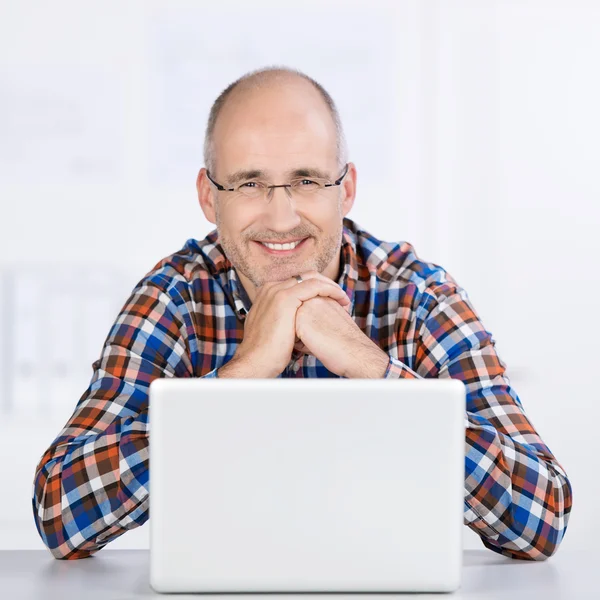 Friendly mature man smiling with a laptop — Stock Photo, Image