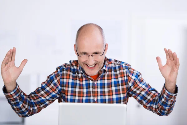 Vrolijke volwassen man op zoek naar een laptop scherm — Stockfoto