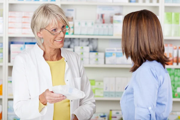 Farmacêutico dando medicamentos prescritos ao cliente na farmácia — Fotografia de Stock