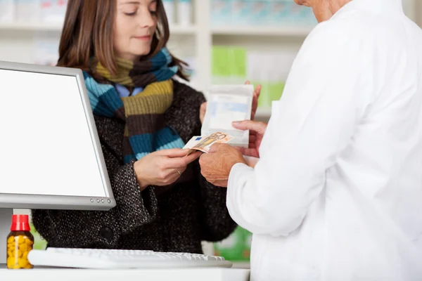 Farmacéutica que recibe dinero de una clienta femenina para medicamentos — Foto de Stock