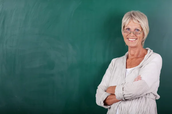 Teacher With Arms Crossed Standing Against Chalkboard — Stock Photo, Image