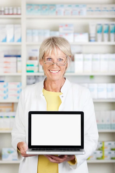 Farmacéutica femenina que muestra el ordenador portátil en la farmacia — Foto de Stock