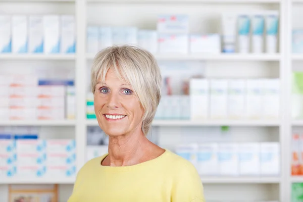 Старша жінка фармацевт посміхається в аптеці — стокове фото