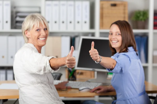 Empresárias Gesturing Thumbs Up At Desk — Fotografia de Stock