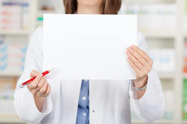 Farmacista Holding Pen durante la visualizzazione di carta bianca in farmacia — Foto Stock