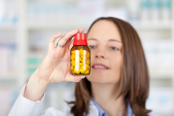 Botella de la píldora del sostenimiento del farmacéutico mientras que la mira — Foto de Stock