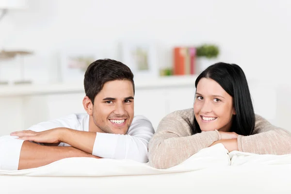 Casal feliz se apoiando no sofá em casa — Fotografia de Stock