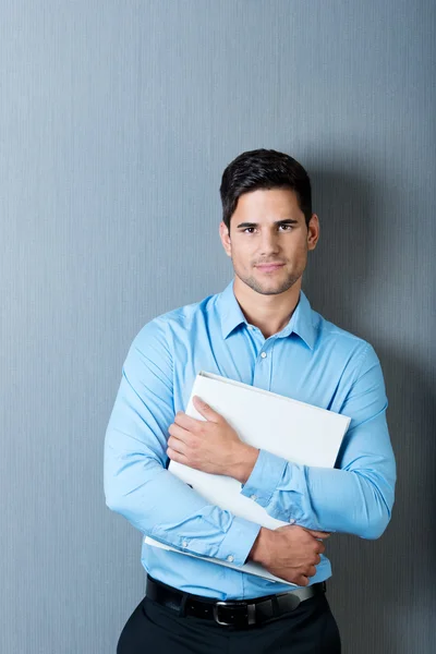 Empresario sosteniendo aglutinante contra pared azul — Foto de Stock