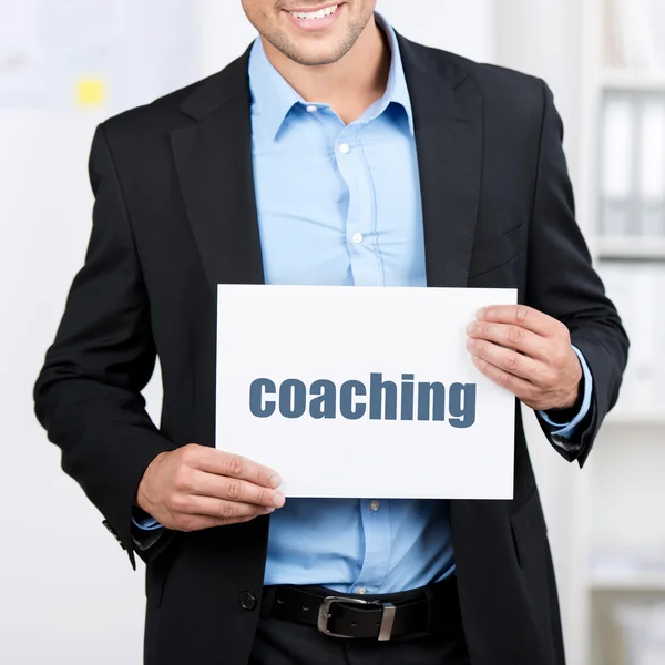 Uomo d'affari che tiene Placard con segno di coaching — Foto Stock