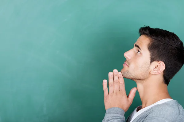 Estudante com as mãos fechadas olhando para fora contra Chalkboard — Fotografia de Stock