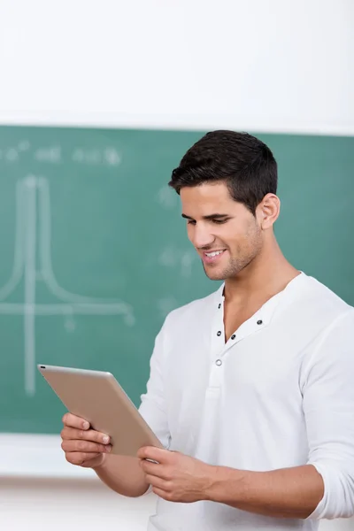 Lächelnder Student beim Lesen seines Tablet-PCs — Stockfoto