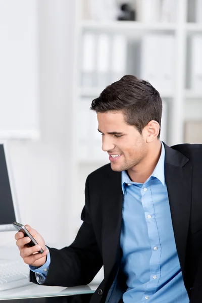 Businessman smiling while looking at his mobile — Stock Photo, Image