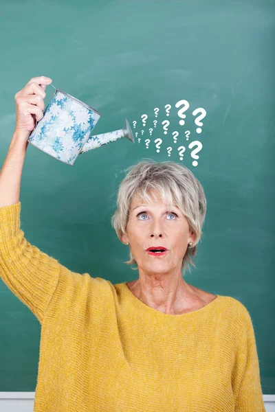 Professor segurando regar lata com pontos de interrogação em Chalkboard — Fotografia de Stock