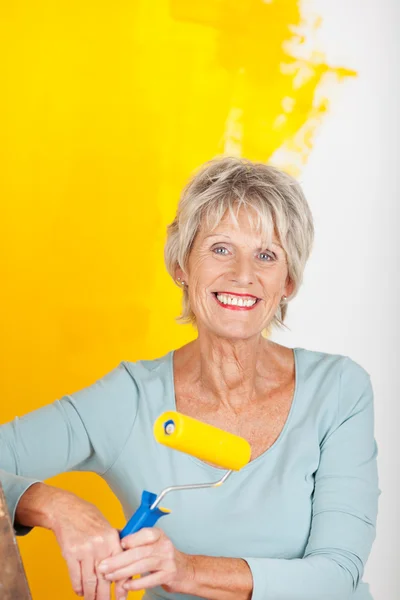 Mature woman painting in yellow — Stock Photo, Image