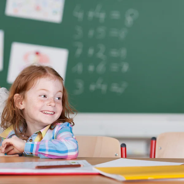 Kleine Schülerin lächelt im Klassenzimmer — Stockfoto