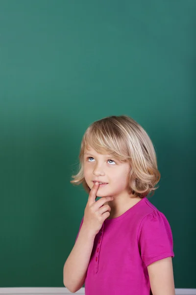 Schoolmeisje denken voor het bord — Stockfoto