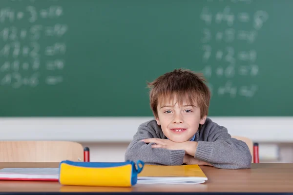 Young boy leaning over the desk in the classroom — Stock Photo, Image