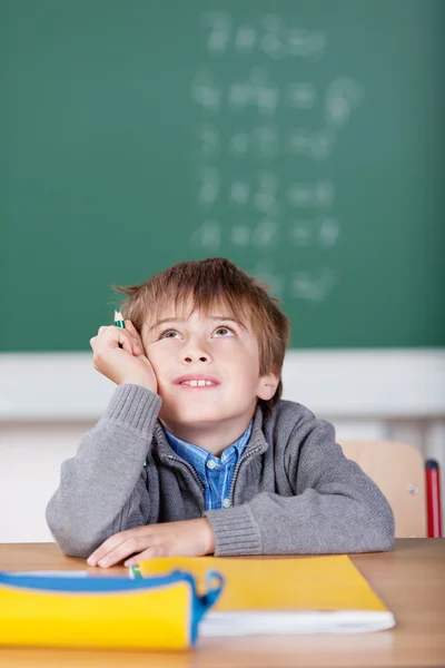 Schoolboy daydreaming when sitting at his desk — Stock Photo, Image