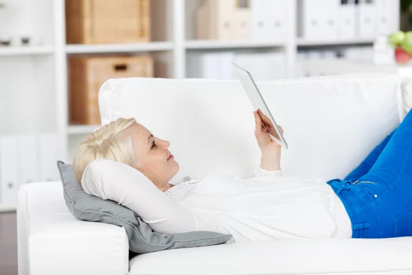Femme détendue lisant ebook sur canapé — Photo