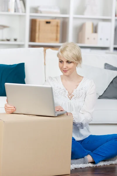 ノート パソコンを見て箱の移動を持つ女性 — ストック写真