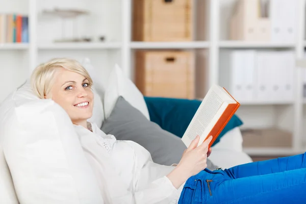 Lächelnde Frau entspannt sich mit einem Buch — Stockfoto