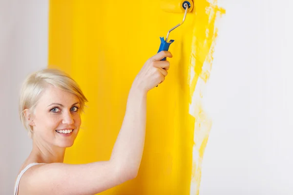 Mulher sorridente pintando a parede — Fotografia de Stock