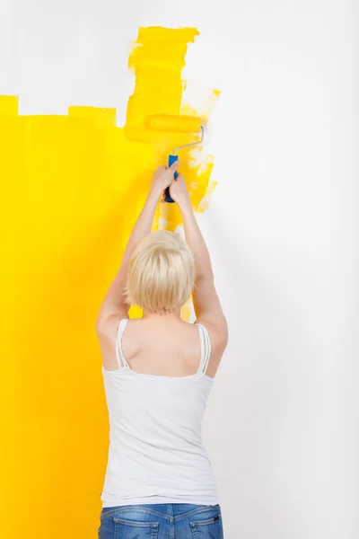 Mulher pintando a parede amarela — Fotografia de Stock