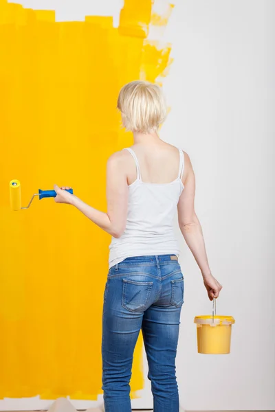 ペイント ローラーと黄色の塗られた壁のバケツを持つ女性 — ストック写真