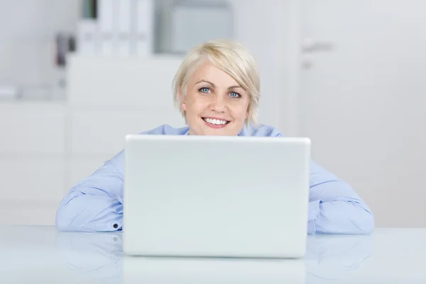 Mujer de negocios feliz mirando hacia arriba por el ordenador portátil en el escritorio — Foto de Stock