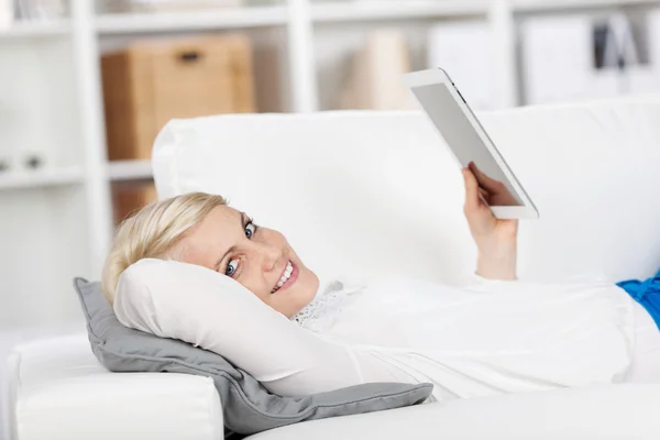 Tablet kanepede yatan genç kadın — Stok fotoğraf