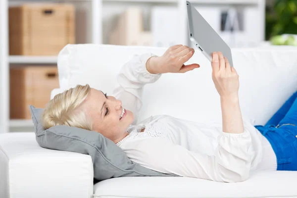 Junge Frau mit Tablet auf Sofa liegend — Stockfoto