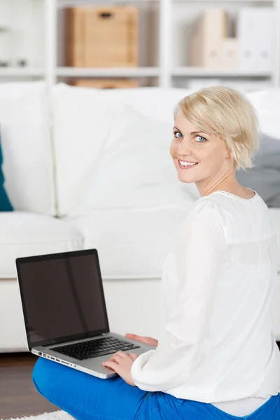 Mooie lachende vrouw met laptop thuis — Stockfoto