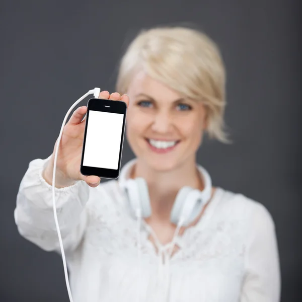Glad kvinna med hörlurar visar smarta telefonen — Stockfoto