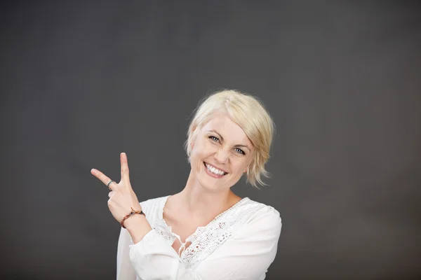 Glada blond kvinna gestikulerande peace-tecken — Stockfoto