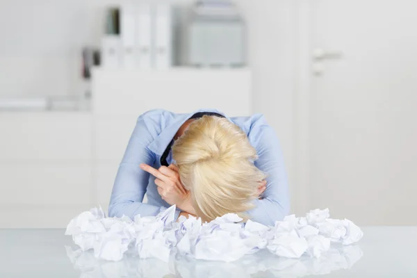 Manager mit dem Kopf in der Hand durch zerknüllte Papierkugeln am Schreibtisch — Stockfoto