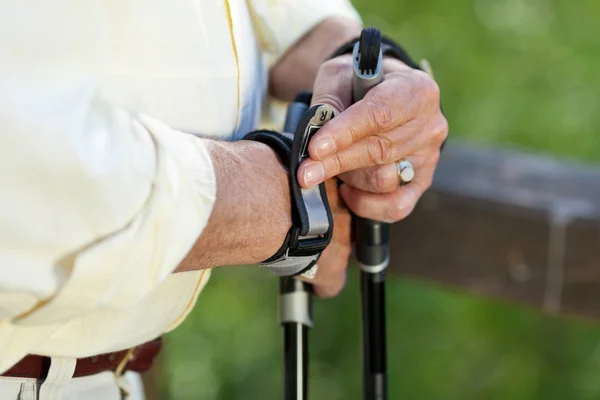 Hombre mayor ajustando correa de poste de senderismo en la mano — Foto de Stock
