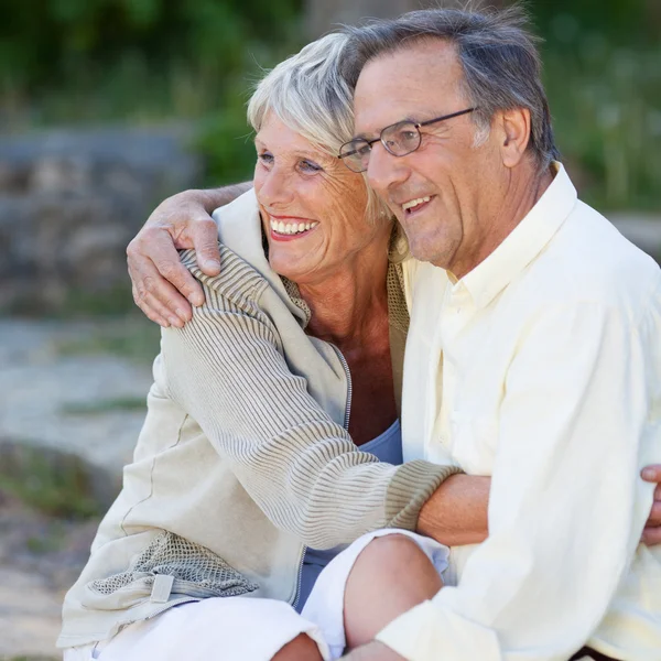 Äldre par tittar bort medan embracing i park — Stockfoto