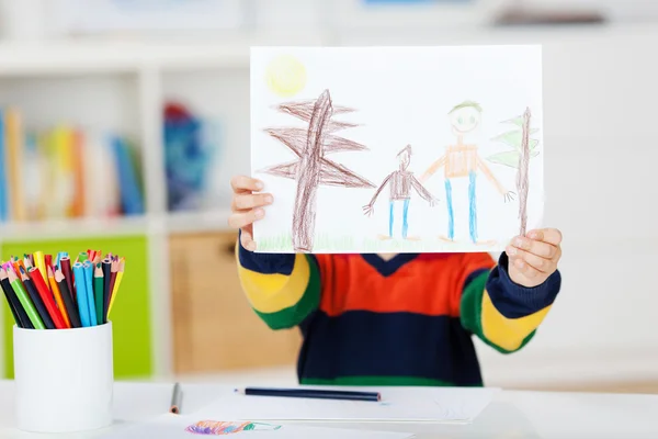Хлопчик показує малюнок за столом — стокове фото