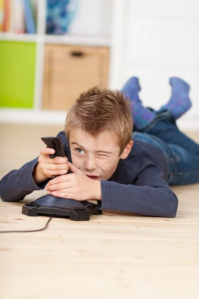 Menino jogando vídeo game enquanto deitado no chão — Fotografia de Stock