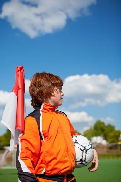 Niño sosteniendo balón de fútbol mientras mira hacia otro lado en la bandera de la esquina — Foto de Stock