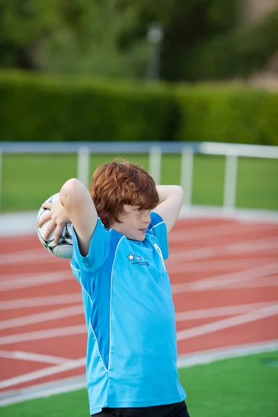 Chłopiec rzucanie piłki na pole — Zdjęcie stockowe
