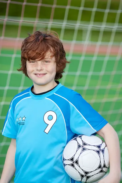Junge hält Fußballball gegen Netz — Stockfoto
