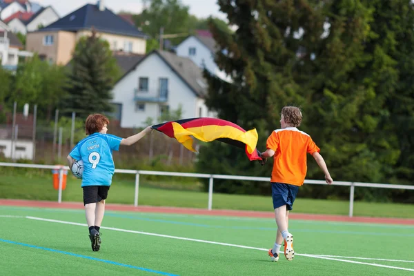 男の子で実行中のドイツ国旗の付いたフィールドを祝う — ストック写真