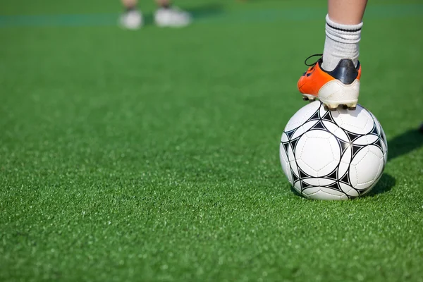 Pojkens ben på fotboll i fältet — Stockfoto