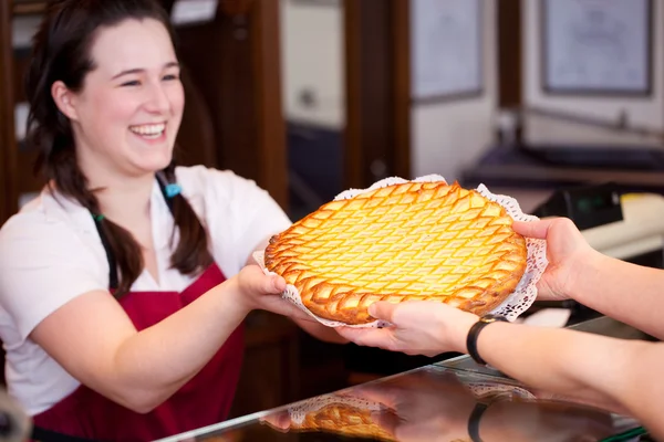 Bakery worker selling an apple tart — Stock Photo, Image