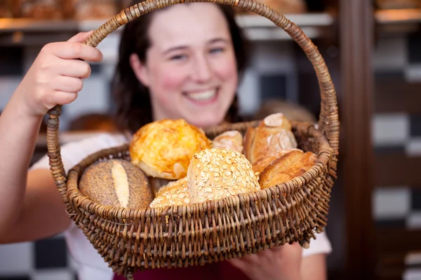 Lavoratore di panetteria sorridente con rotoli in un cesto — Foto Stock