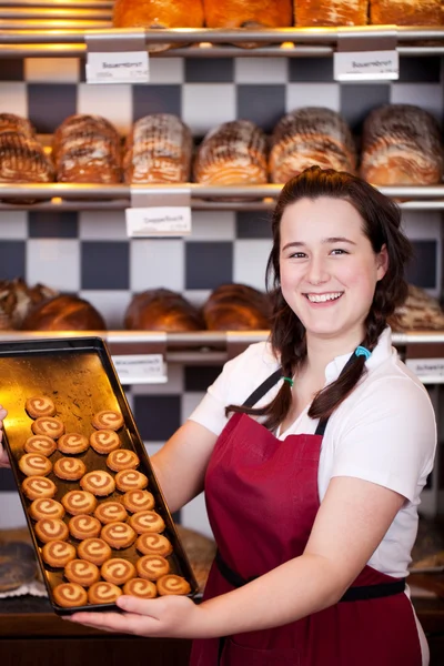 Assistente di panetteria sorridente con biscotti — Foto Stock