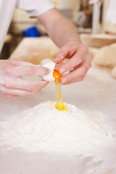Baker works with eggs and flour — Stock Photo, Image