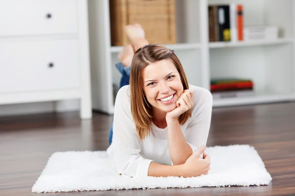 Souriant jeune femme couchée sur le sol et posant — Photo