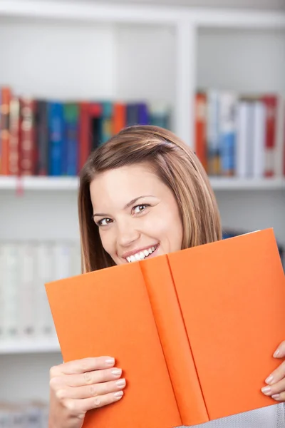 Schöne Frau hält ein Buch und lächelt — Stockfoto